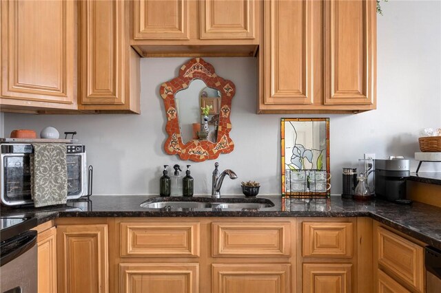 kitchen featuring dark stone countertops, range, and a sink