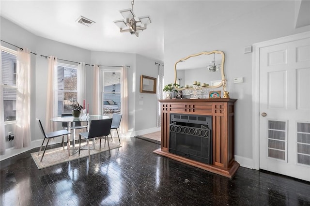 dining area with baseboards, visible vents, wood finished floors, a fireplace, and a notable chandelier