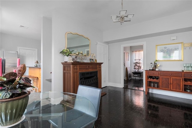 dining room featuring a notable chandelier, a fireplace, visible vents, wood finished floors, and baseboards