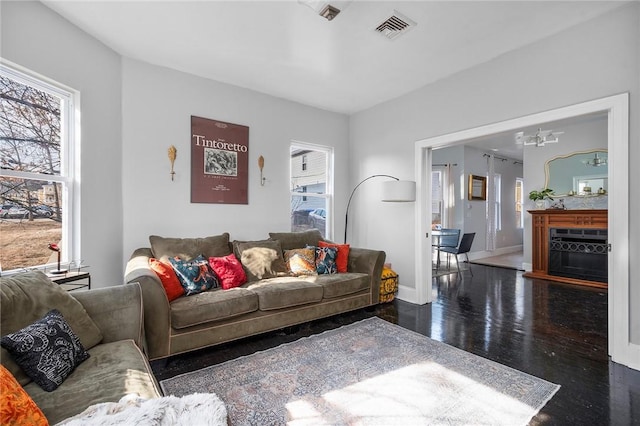 living area with a fireplace, wood finished floors, visible vents, baseboards, and an inviting chandelier