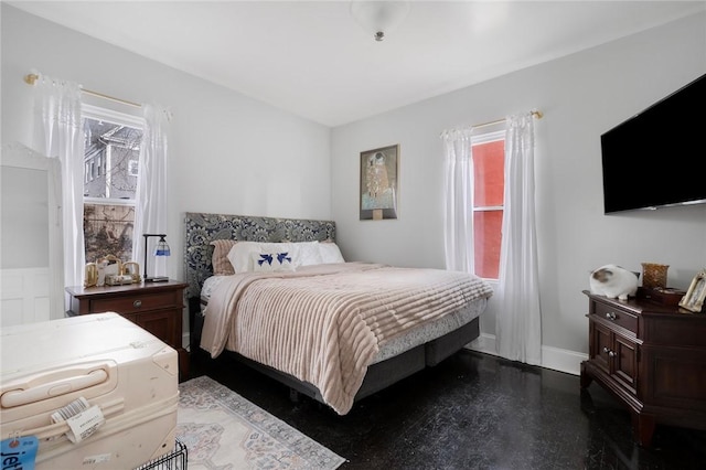 bedroom featuring finished concrete floors, multiple windows, and baseboards