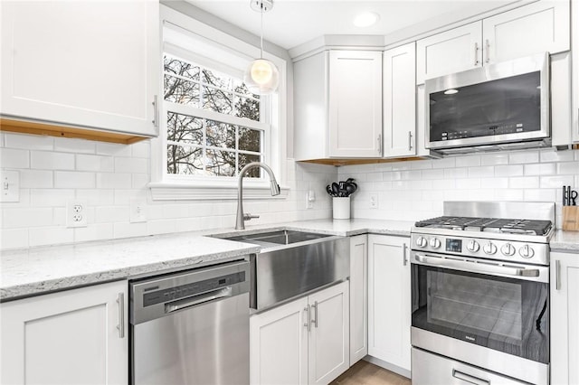 kitchen with stainless steel appliances, a sink, backsplash, and light stone counters