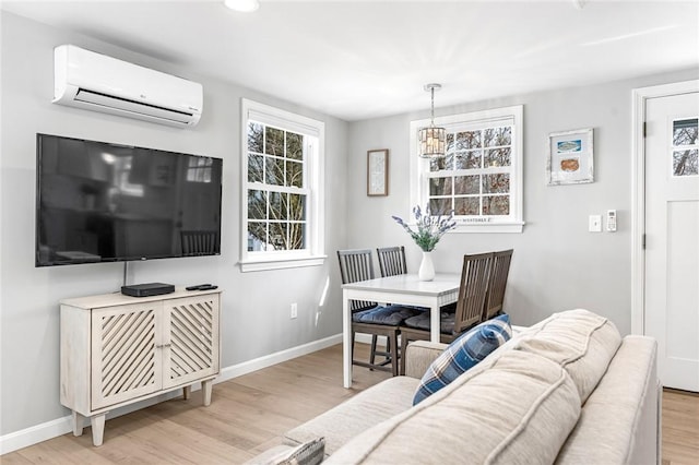 living area featuring a wall unit AC, light wood-style flooring, and baseboards