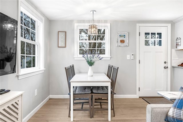 dining space with light wood finished floors, baseboards, and a notable chandelier