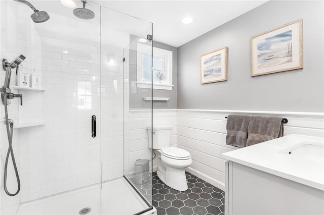 bathroom with a wainscoted wall, a shower stall, and toilet