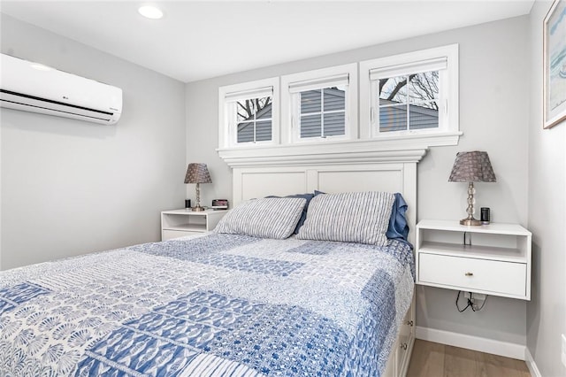 bedroom with recessed lighting, baseboards, wood finished floors, and a wall mounted air conditioner