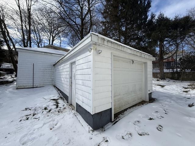 snow covered structure with an outbuilding