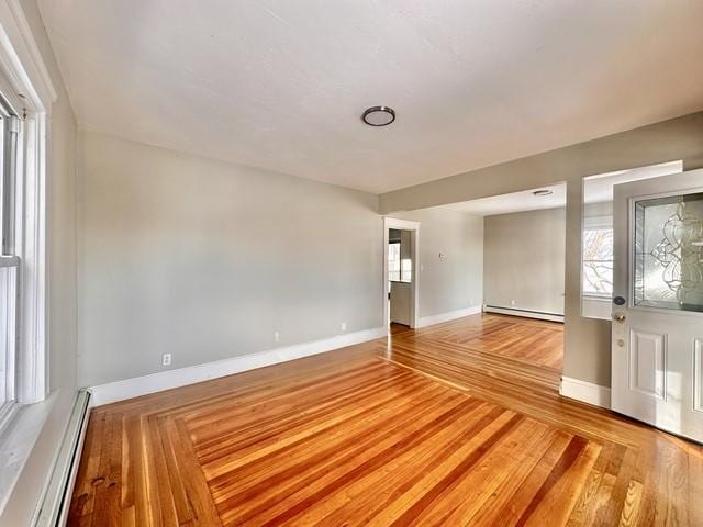 empty room with baseboard heating, parquet flooring, and baseboards