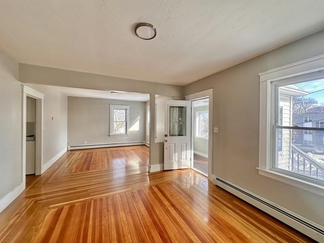 interior space featuring light wood-style floors, a baseboard radiator, and baseboards