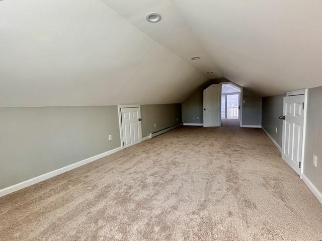 additional living space featuring lofted ceiling, a baseboard heating unit, baseboards, and carpet flooring