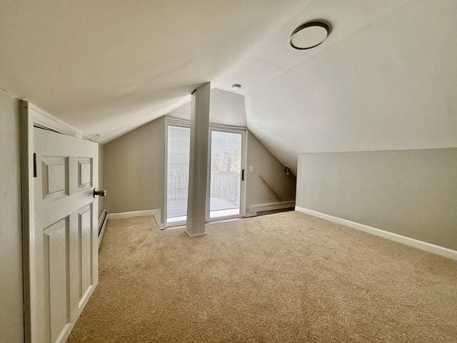 additional living space with baseboards, vaulted ceiling, and light colored carpet