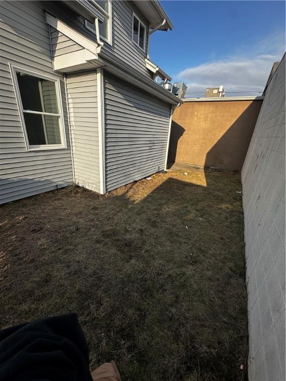 view of side of home with a yard and fence