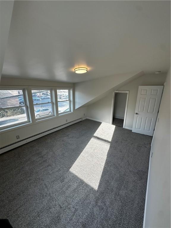 bonus room with dark colored carpet and baseboard heating