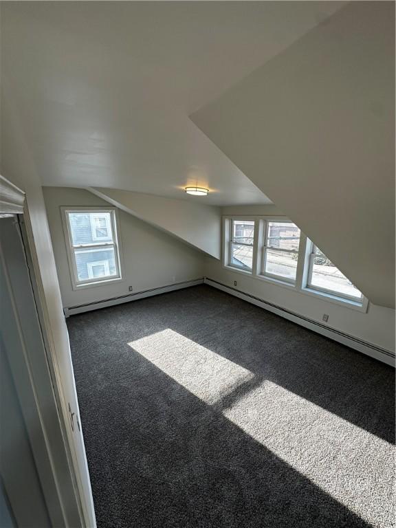 bonus room featuring lofted ceiling, dark colored carpet, plenty of natural light, and a baseboard radiator