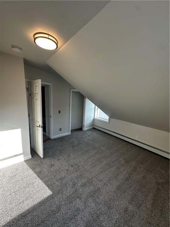 additional living space featuring a baseboard heating unit, carpet, lofted ceiling, and baseboards