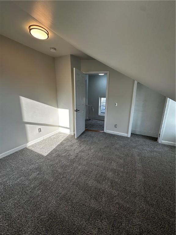 empty room featuring lofted ceiling, carpet, and baseboards