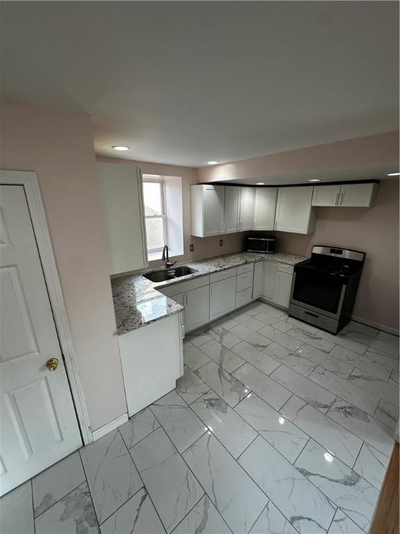 kitchen featuring light stone counters, marble finish floor, stainless steel appliances, a sink, and baseboards