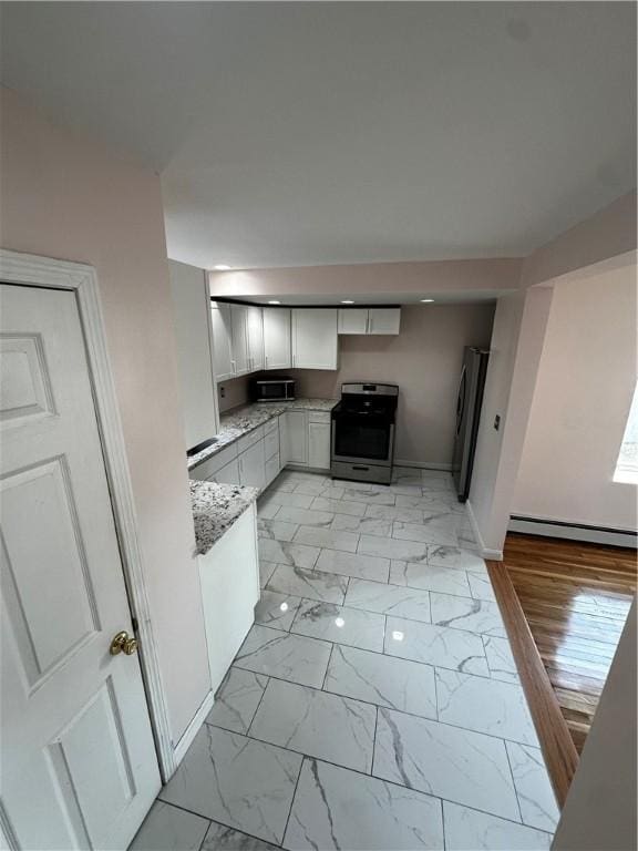 kitchen featuring marble finish floor, a baseboard radiator, appliances with stainless steel finishes, white cabinetry, and baseboards