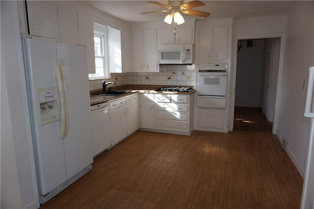 kitchen featuring a warming drawer, light wood finished floors, decorative backsplash, a sink, and white appliances