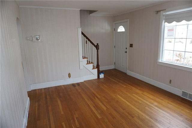 entrance foyer featuring baseboards, visible vents, wood finished floors, stairs, and crown molding