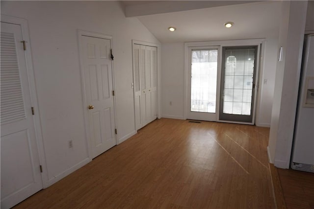 interior space with vaulted ceiling with beams, wood finished floors, and baseboards