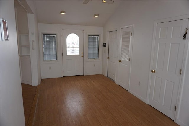 entryway with light wood-style floors, vaulted ceiling, and baseboards