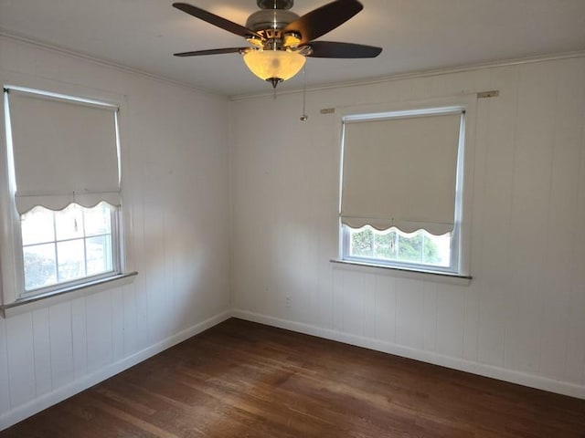 spare room with a ceiling fan, crown molding, baseboards, and wood finished floors