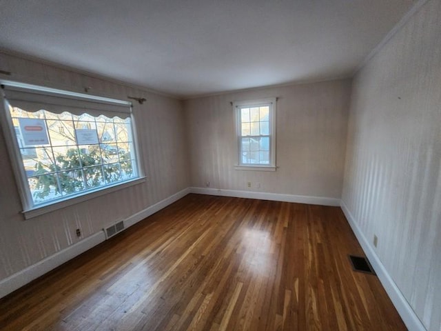 spare room with visible vents, baseboards, and wood finished floors