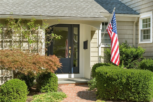 entrance to property with a porch and roof with shingles