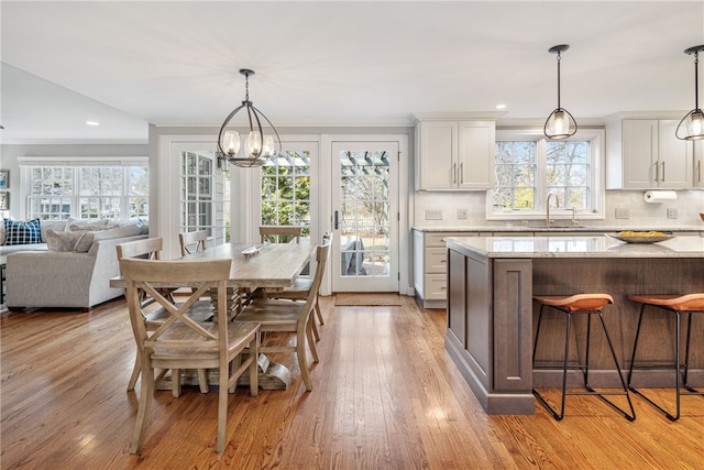 dining space with an inviting chandelier, crown molding, recessed lighting, and light wood-type flooring