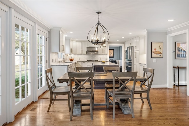 dining area with a notable chandelier, ornamental molding, wood finished floors, recessed lighting, and baseboards