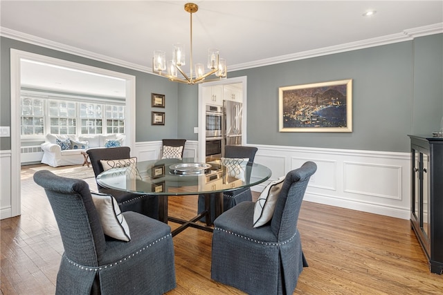 dining room featuring light wood-type flooring, a notable chandelier, and crown molding