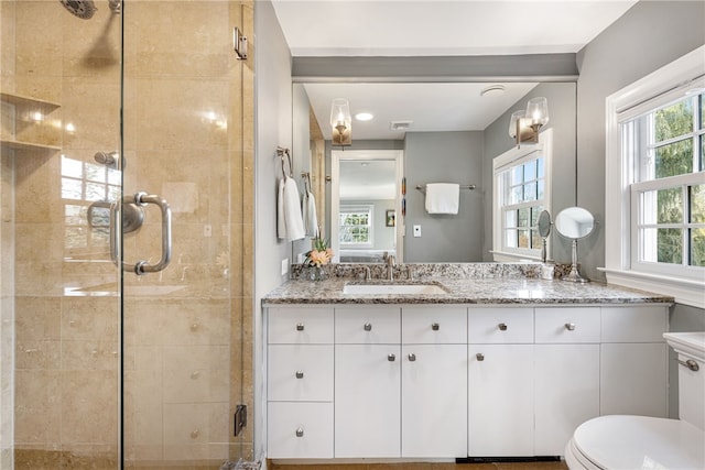 bathroom featuring vanity, toilet, visible vents, and a stall shower