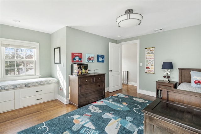 bedroom with wood finished floors, visible vents, and baseboards