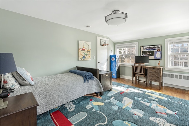 bedroom featuring radiator, baseboards, and wood finished floors