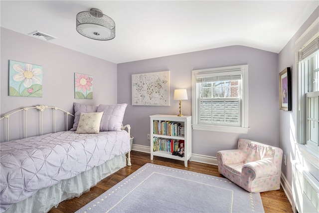 bedroom with visible vents, baseboards, lofted ceiling, and wood finished floors