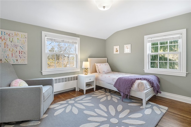 bedroom featuring lofted ceiling, radiator, wood finished floors, and baseboards