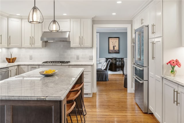 kitchen with light wood-style flooring, ornamental molding, under cabinet range hood, white cabinetry, and stainless steel appliances