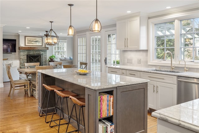 kitchen with a breakfast bar area, dishwasher, white cabinetry, and a sink