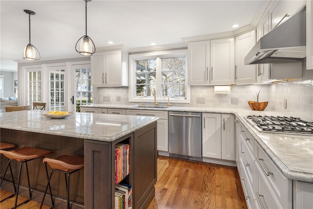 kitchen featuring under cabinet range hood, a kitchen bar, white cabinets, stainless steel appliances, and a sink