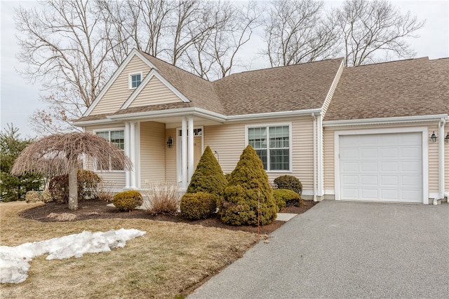 view of front of home with driveway, a shingled roof, and an attached garage