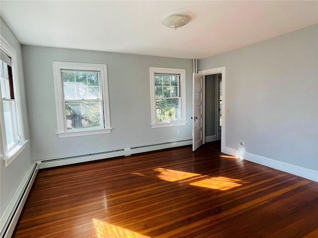 spare room with a baseboard heating unit, a baseboard radiator, wood finished floors, and a healthy amount of sunlight