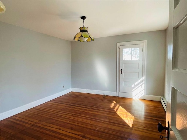 spare room with a baseboard heating unit, wood finished floors, and baseboards