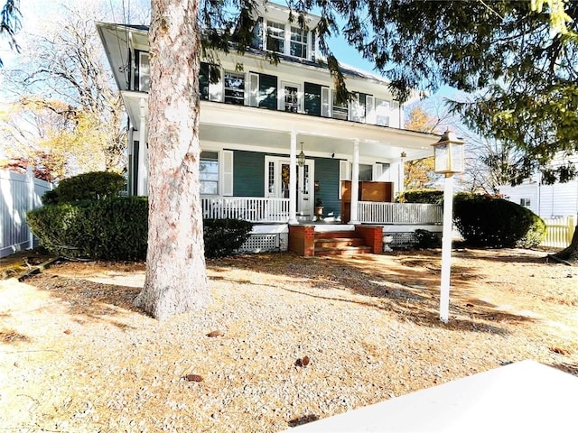 american foursquare style home featuring a porch and fence