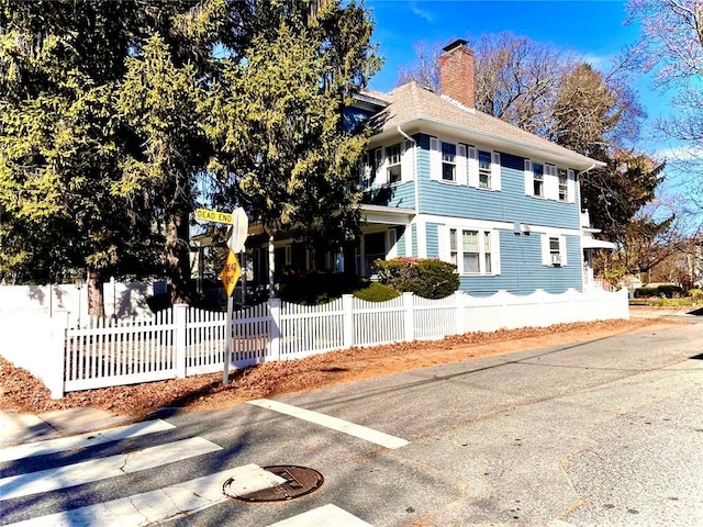 view of home's exterior featuring a fenced front yard and a chimney