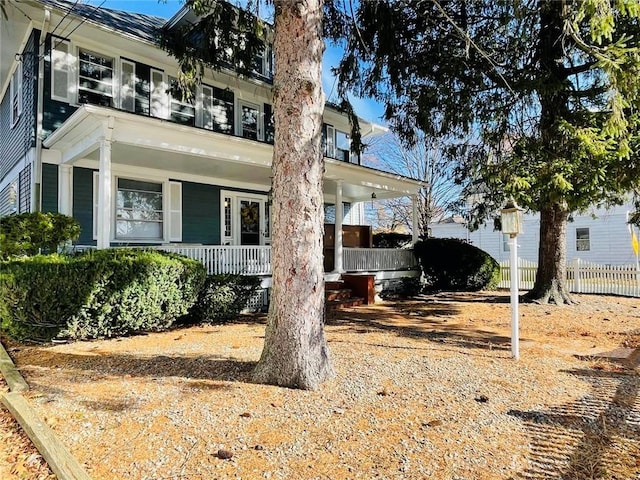 view of home's exterior with covered porch, fence, and a balcony