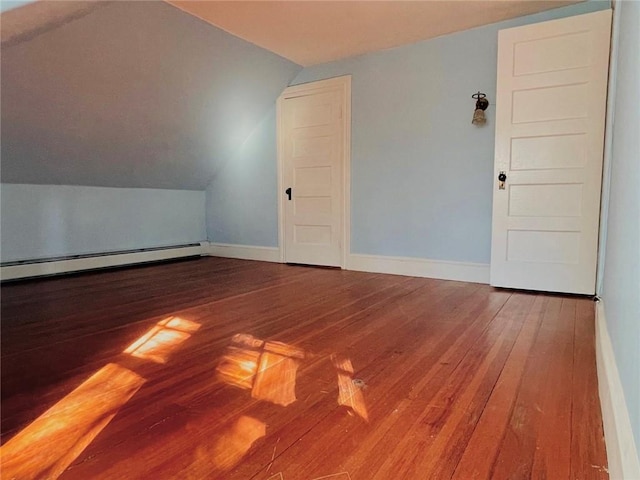 additional living space with vaulted ceiling, hardwood / wood-style floors, baseboard heating, and baseboards