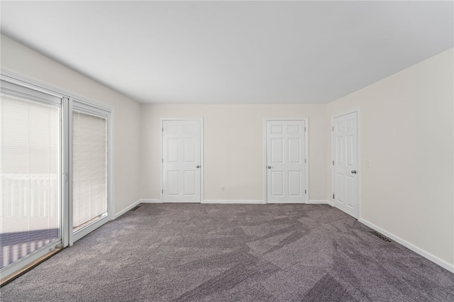 unfurnished bedroom with baseboards, multiple windows, carpet flooring, and access to exterior