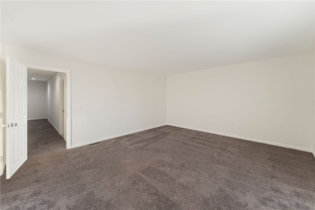 unfurnished room with dark colored carpet and baseboards