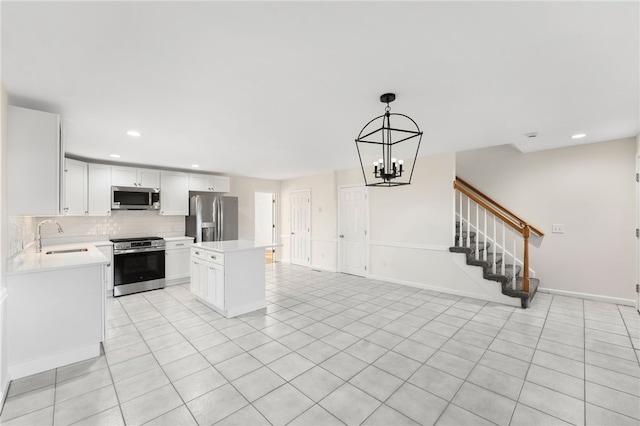 kitchen with appliances with stainless steel finishes, light countertops, a sink, and backsplash